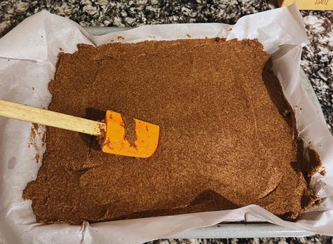 Spreading horse treat dough evenly on a parchment-lined baking tray