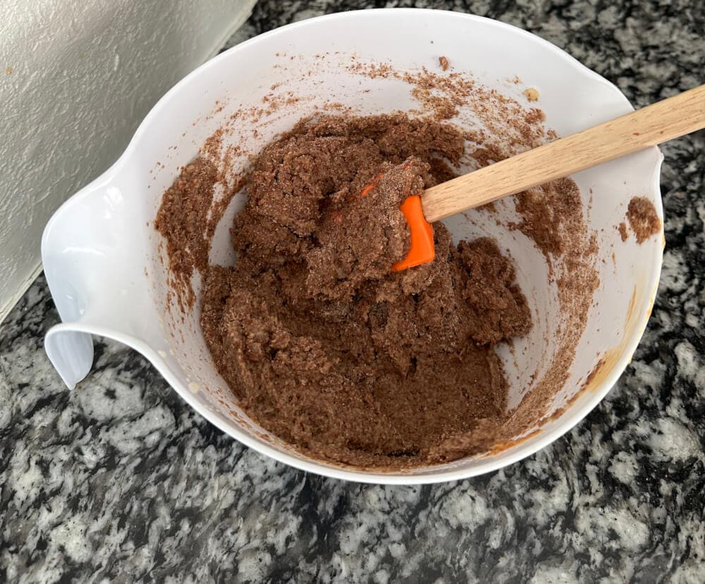 Combining peanut butter dough mixture in a bowl with a spatula