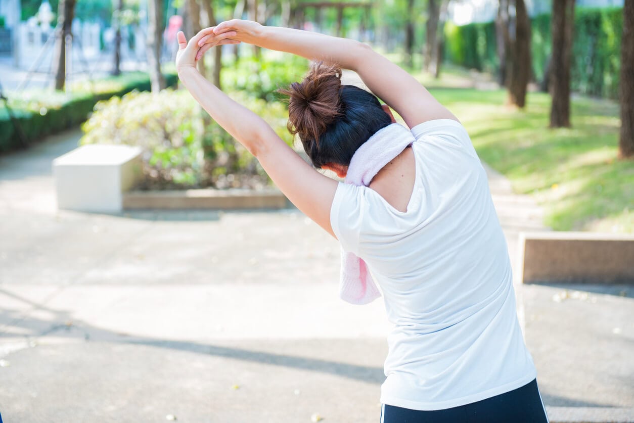image of woman performing shoulder expansion stretches, pictured from, behind