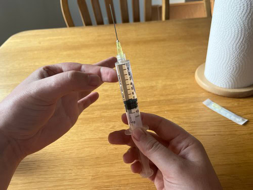 flicking a syringe to move air bubbles to the needle tip